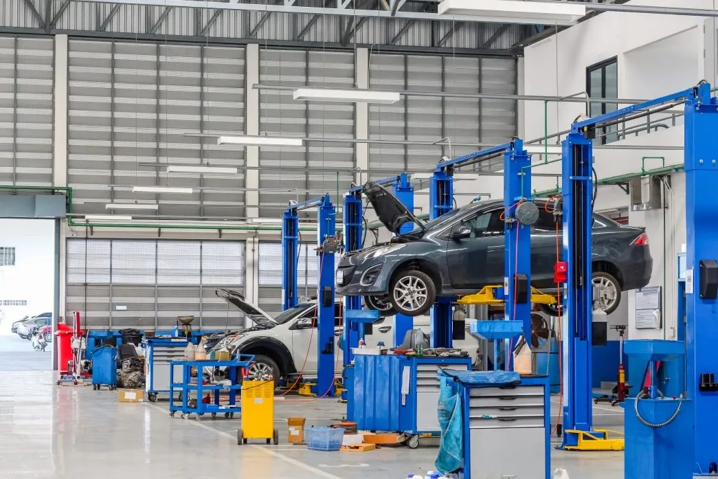 Two-post vehicle lifts in a high-ceiling automotive shop with a car raised overhead